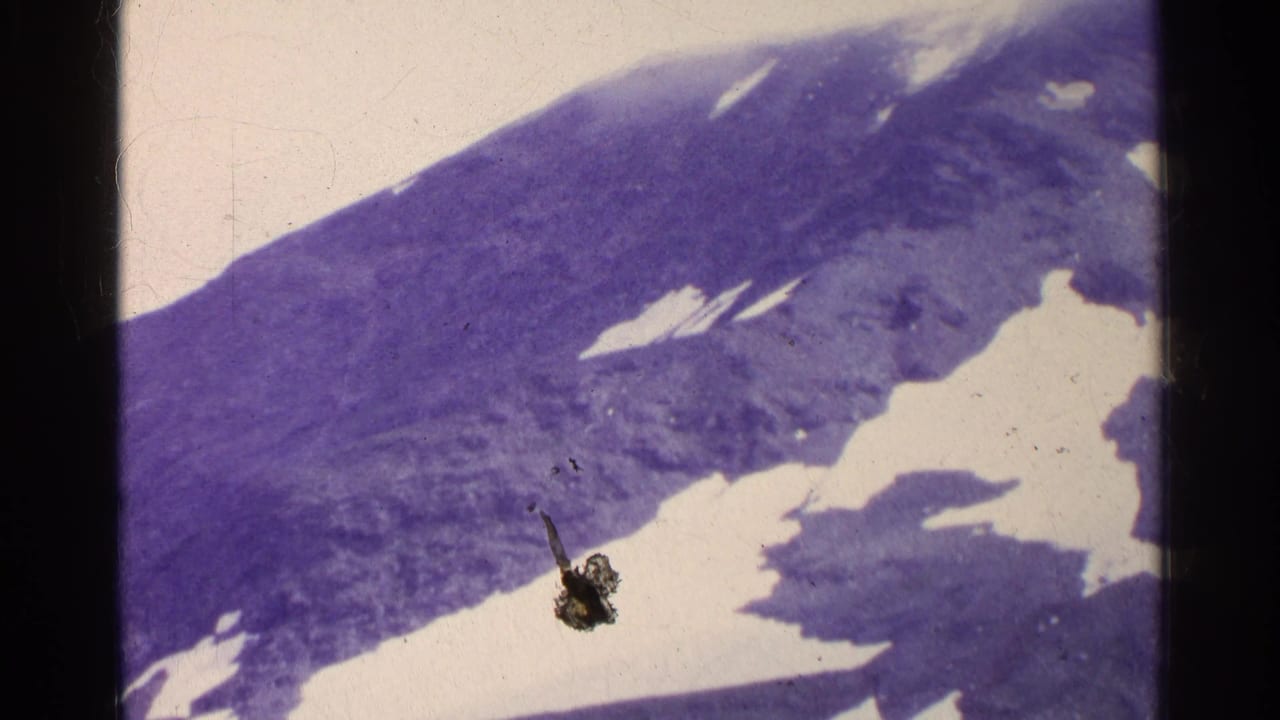 Snow patches on a dark mountain slope with visible film borders and scratches.