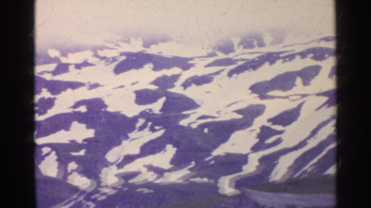 1961 Swiss mountain landscape filmed from above, with broken snow cover and grainy 8mm texture.