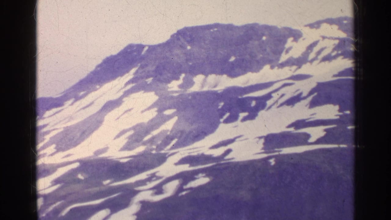 1961 Switzerland 8mm frame showing a broad rocky slope crossed by snow bands, with aged purple film tint and soft detail.