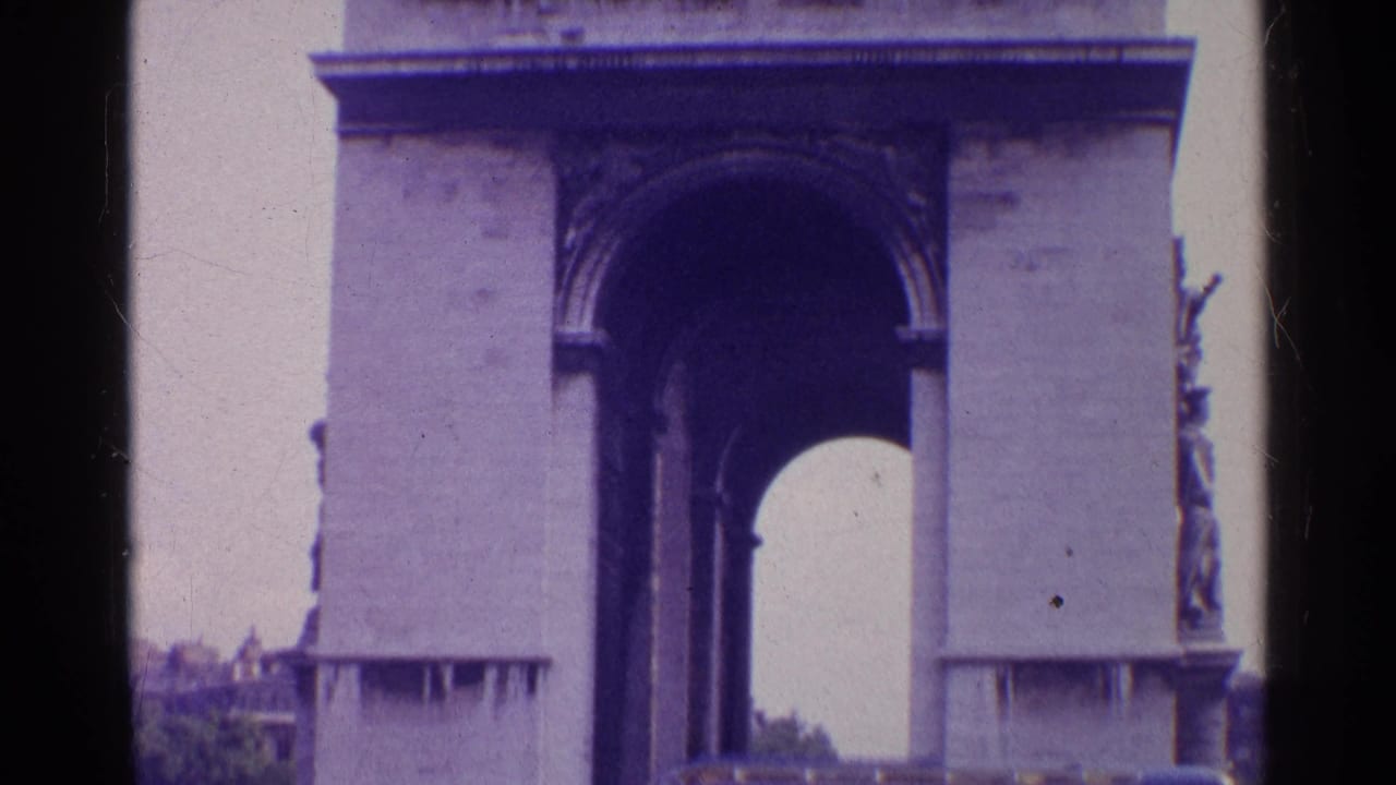 Closer 8mm view of the monumental stone arch in Switzerland, with the dark arch opening, side sculpture, and trees at the edge of frame.