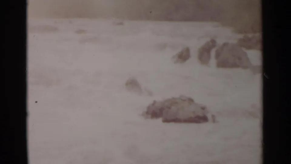 Soft 8mm frame of churning river water with scattered rocks, consistent with the supplied 1962 Jamestown, Virginia home-movie metadata.