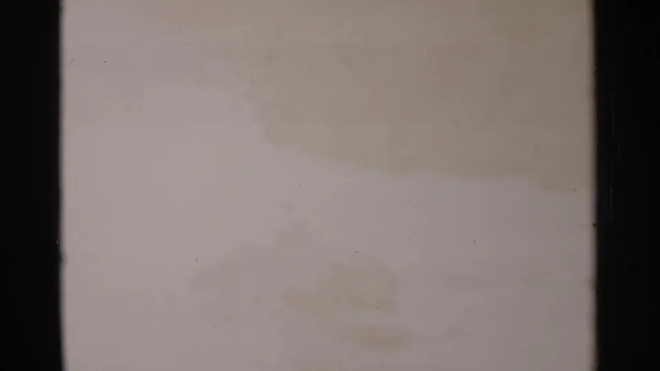 Washed-out 8mm view of bright rushing water, with faint texture from rocks or spray and visible film-edge darkness.