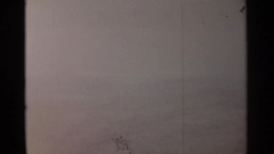 1962 8mm home-movie frame of distant hazy hills and sky, with dark film borders and visible scratches.