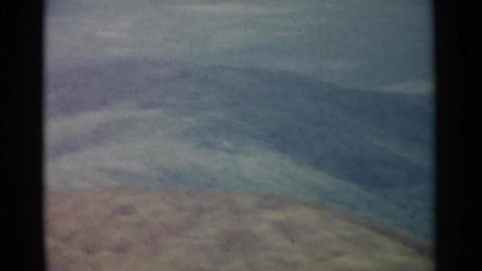 1962 8mm home-movie frame of rolling blue-gray hills, softened by haze and aged film texture.