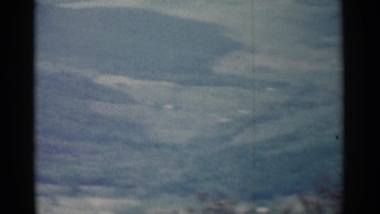 Distant rolling hills under a cloudy sky with dark film-frame edges.