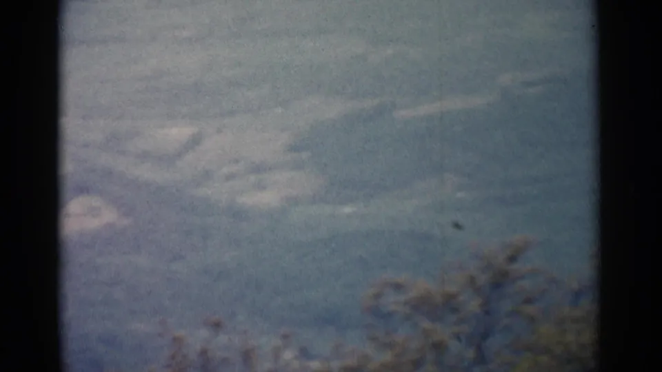 1962 8mm home-movie frame near Jamestown showing treetops below a misty rolling landscape.