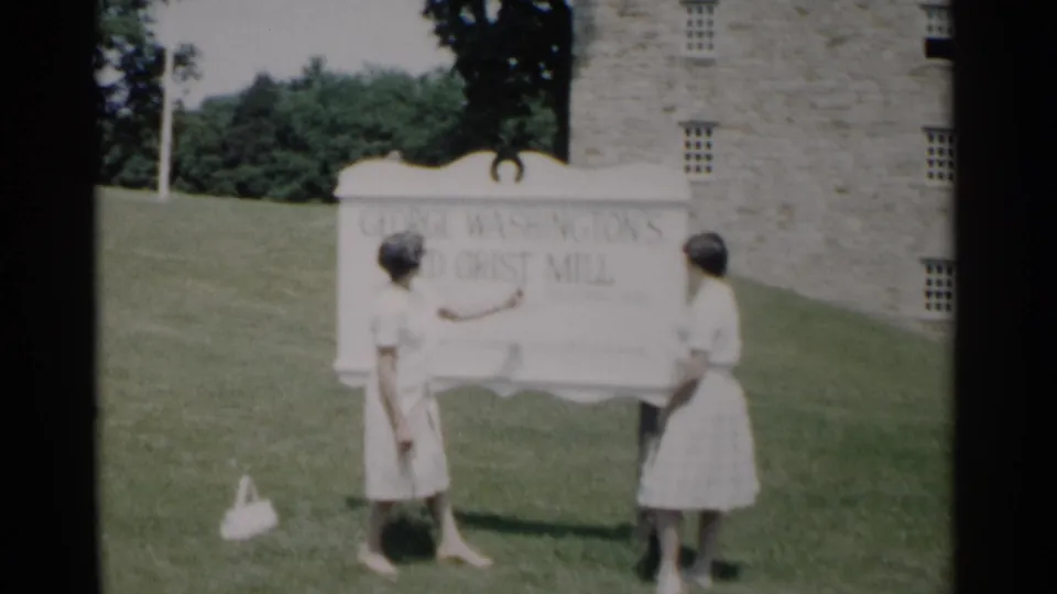 The final frame shows two women posed at the George Washington's Old Grist Mill sign with lawn, trees, and stonework behind them.