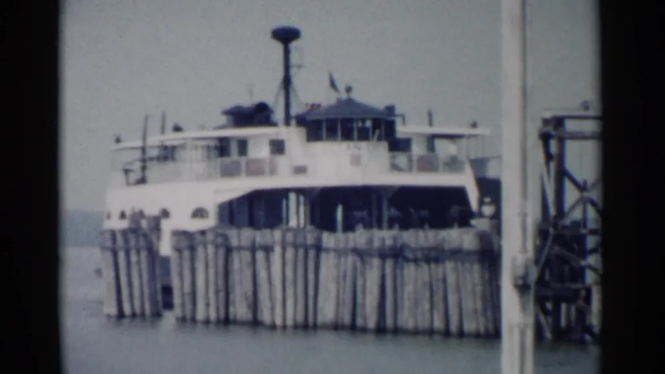 A white ferry sits at a wooden pier in Jamestown, Virginia, shown in soft 1962 8mm home-movie footage.