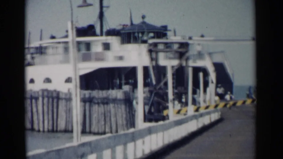 1962 Jamestown, Virginia frame of a docked ferry seen from the pier, with ramp equipment and railing visible.