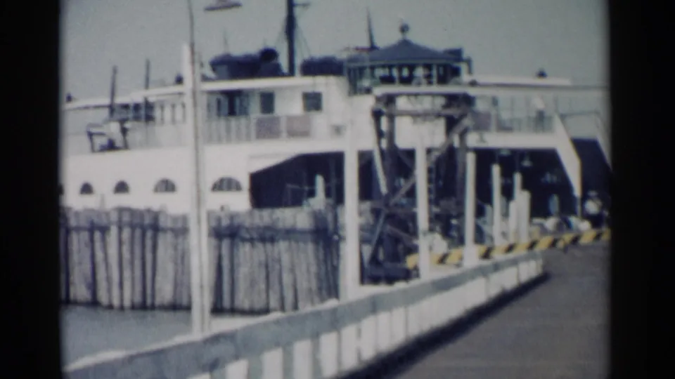 White passenger ferry at the Jamestown pier in 1962, viewed across the walkway with ramp equipment and railings in the foreground.