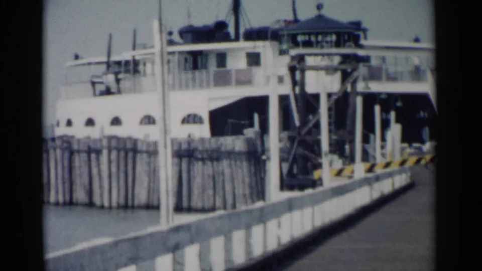 Jamestown ferry scene from 1962 showing the vessel docked beside weathered pier fencing and a ramp structure.
