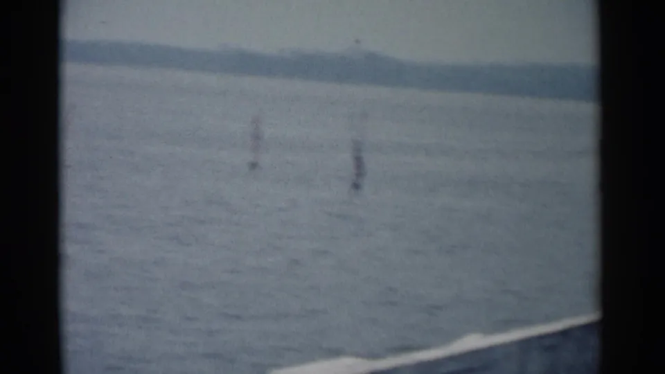 1962 Jamestown, Virginia home-movie frame showing calm river water, distant shoreline, and small water markers through soft 8mm framing.