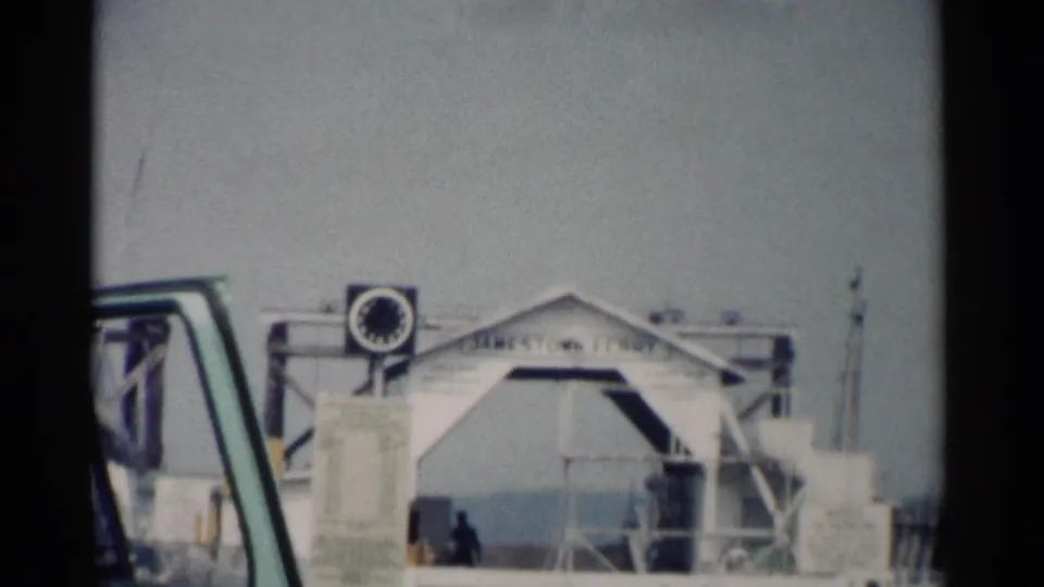 1962 Jamestown ferry landing frame showing the white dock structure, ramp area, railings, and a vehicle window at the left edge.