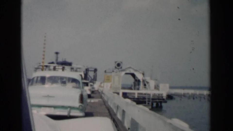 From a vehicle viewpoint, a white sedan, ferry loading structure, dock railings, and water are visible at the Jamestown ferry landing.