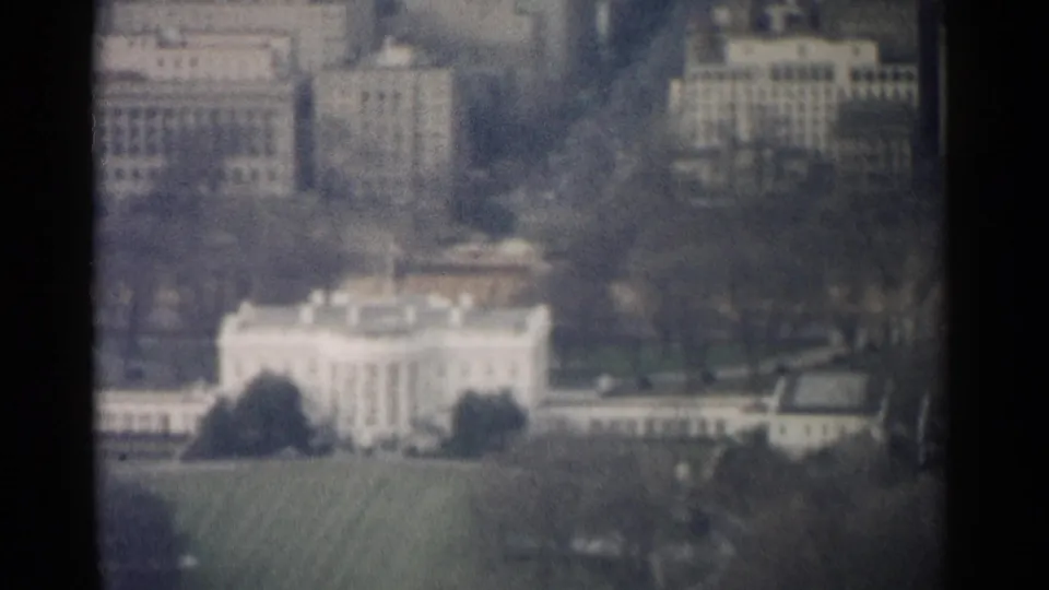 1962 aerial home-movie frame showing the White House and adjacent Washington, DC buildings from above.