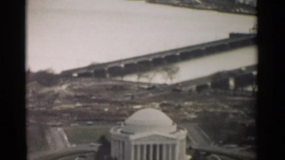 Soft color 8mm view of the Jefferson Memorial in Washington, DC, framed by bridge spans, water, roads, and winter trees.