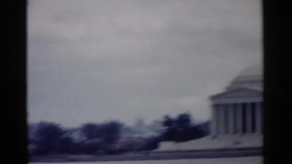 The Jefferson Memorial appears beside water in 1962 Washington DC 8mm footage, with its dome and columns softened by motion blur.