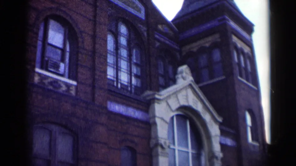 Washington, DC school exterior in 1962, framed on the brick facade, upper windows, and pale arched doorway.