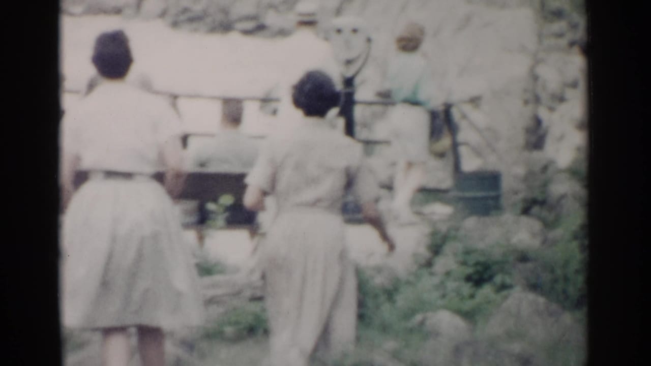 Two women seen from behind near viewfinders and rocky landscaping.