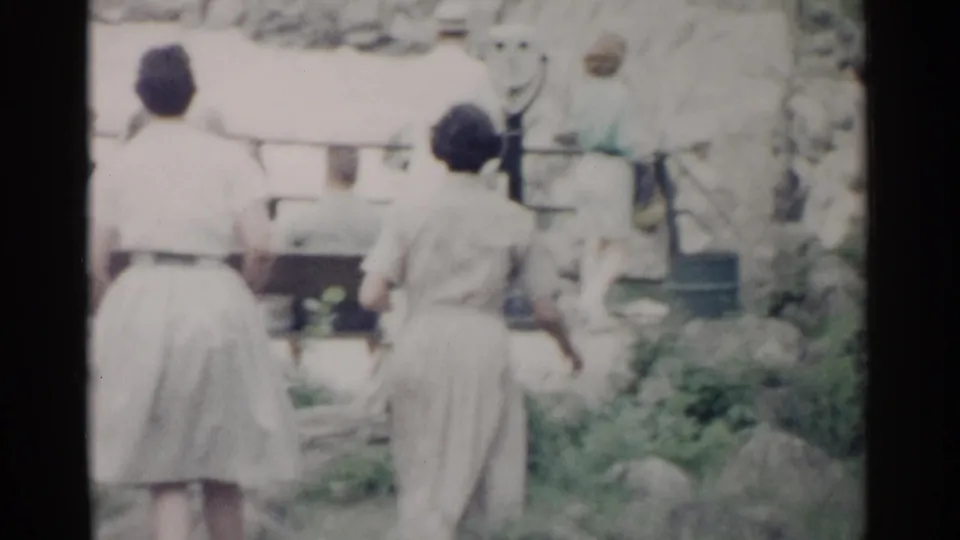 Two women in light summer dresses walk near coin-operated viewfinders at a Washington DC scenic overlook in 1962 home-movie footage.