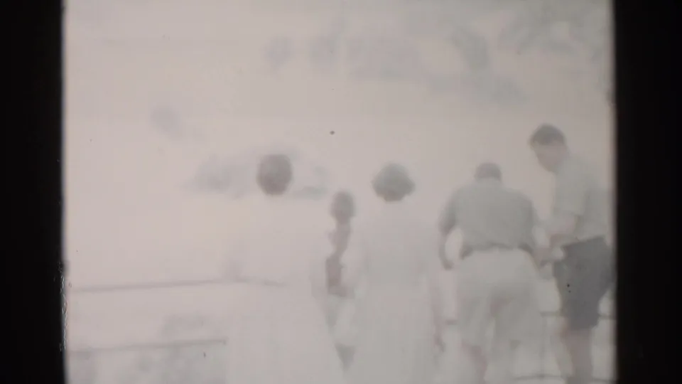 Adults stand near a railing and viewfinder at a scenic overlook, softened by overexposure in 1962 Washington DC home-movie footage.
