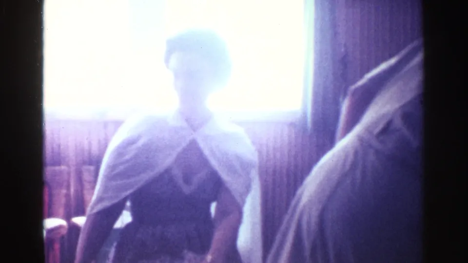 1963 Kentucky frame with a woman in a white shawl silhouetted by window light in a private paneled room.