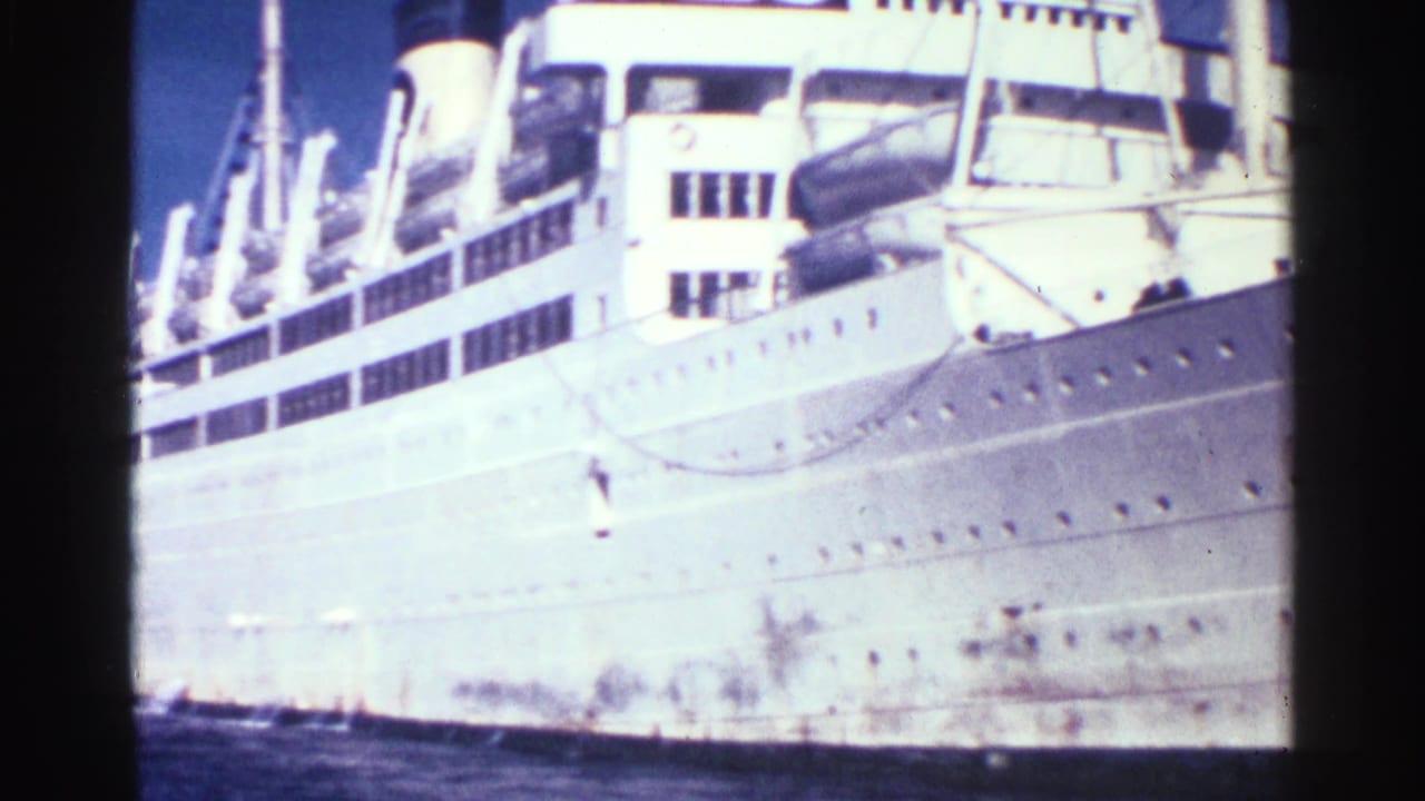 White ocean liner hull and upper decks seen in bright sun.