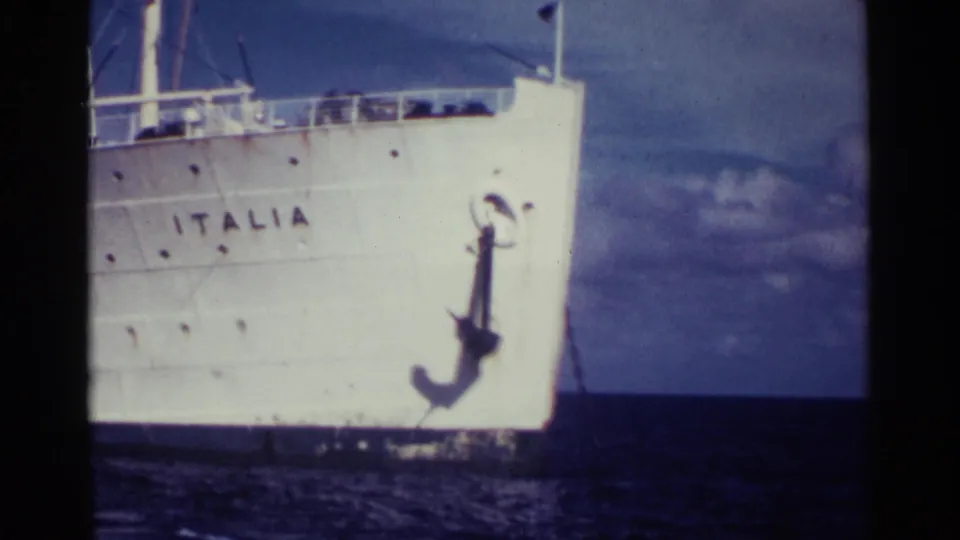The Italia's bow fills the frame, showing the painted name, anchor, portholes, and railings in soft 8mm color.
