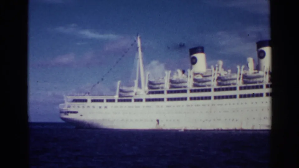 The Italia is seen broadside in a soft 8mm frame, with its white hull, twin funnels, and upper decks visible at sea.