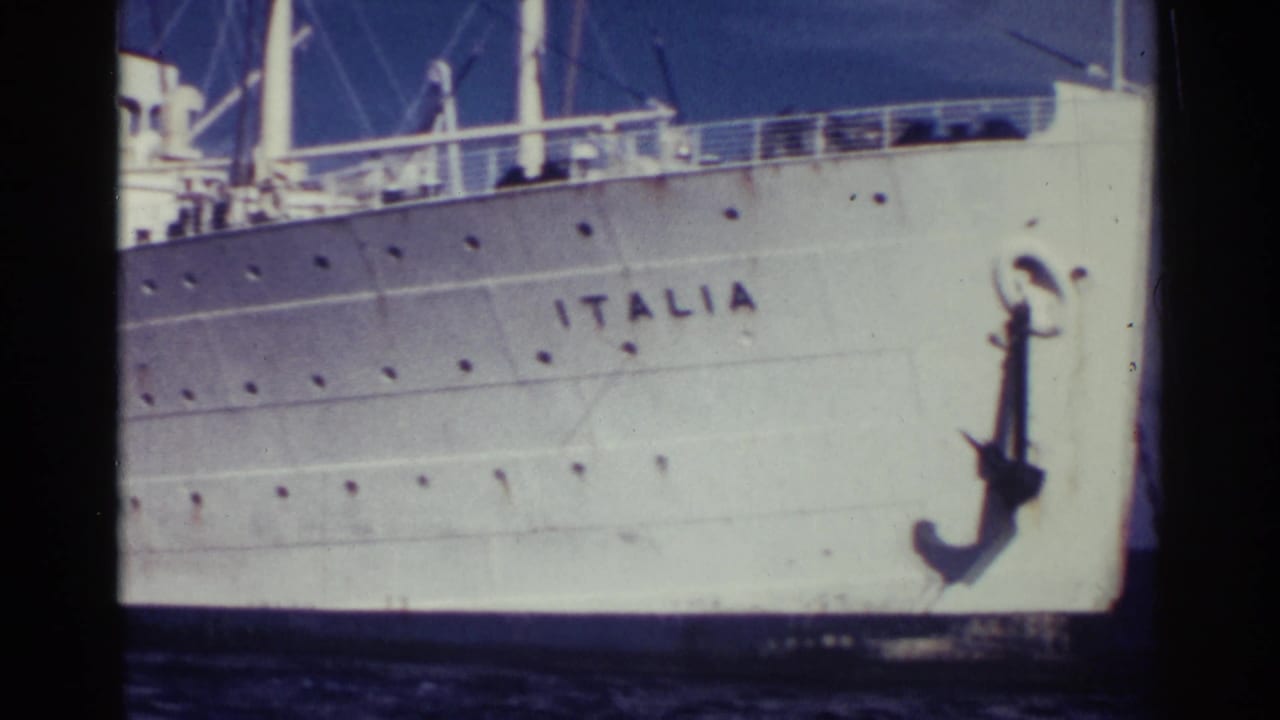 1963 Nassau home-movie frame showing the white bow of the Italian ocean liner Italia, with its name painted on the hull and a large anchor near the waterline.