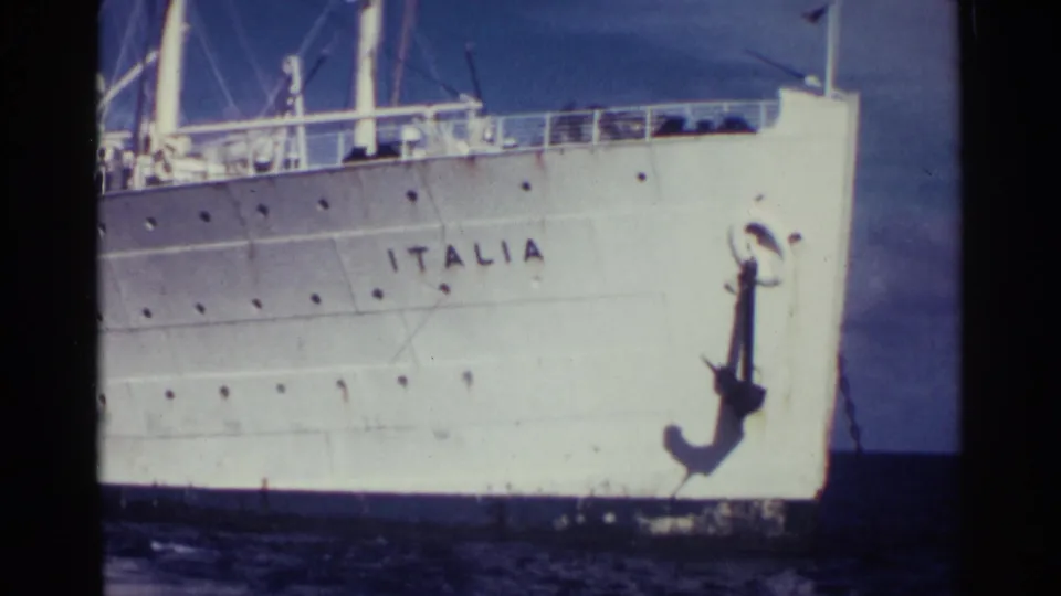 Close 8mm view of the Italia liner's bow in Nassau, with the vessel name legible, the anchor mounted forward, and open water below.