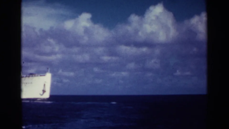 1963 Nassau footage frame with the liner nearly out of view, leaving open water, horizon, and cumulus clouds.