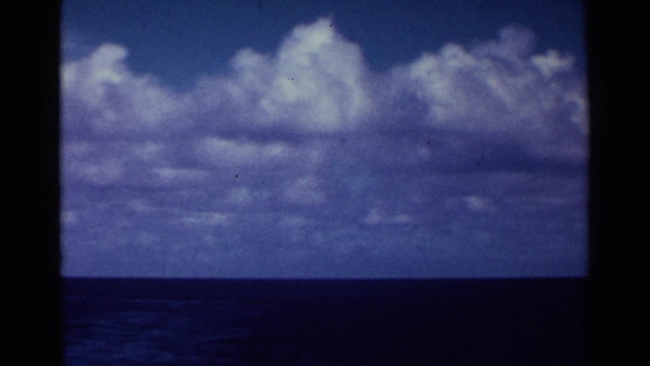 Blue ocean horizon under large white clouds with dark 8mm frame edges.