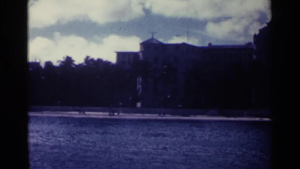 Distant Nassau shoreline with a large waterfront building and towered roofline seen across blue water.