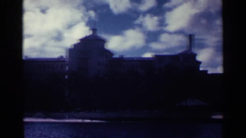 Distant Nassau waterfront building in deep shadow, with bright clouds and blue water in the foreground.