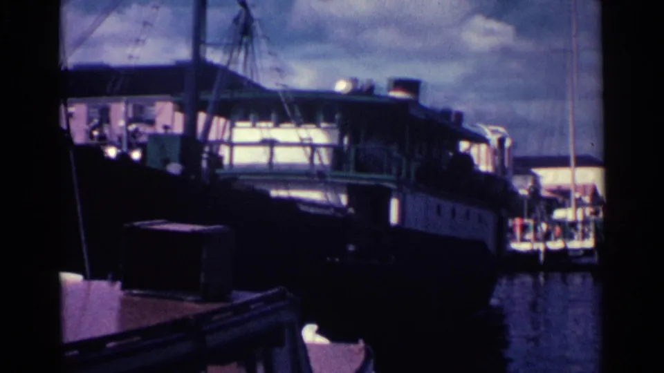 A large docked vessel occupies the Nassau waterfront, with palm silhouettes and cloudy sky beyond.