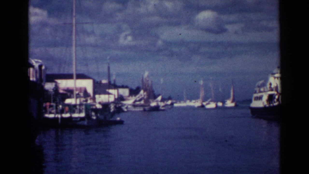 Harbor view with sailboats, dock structures, and a larger vessel at the right edge.