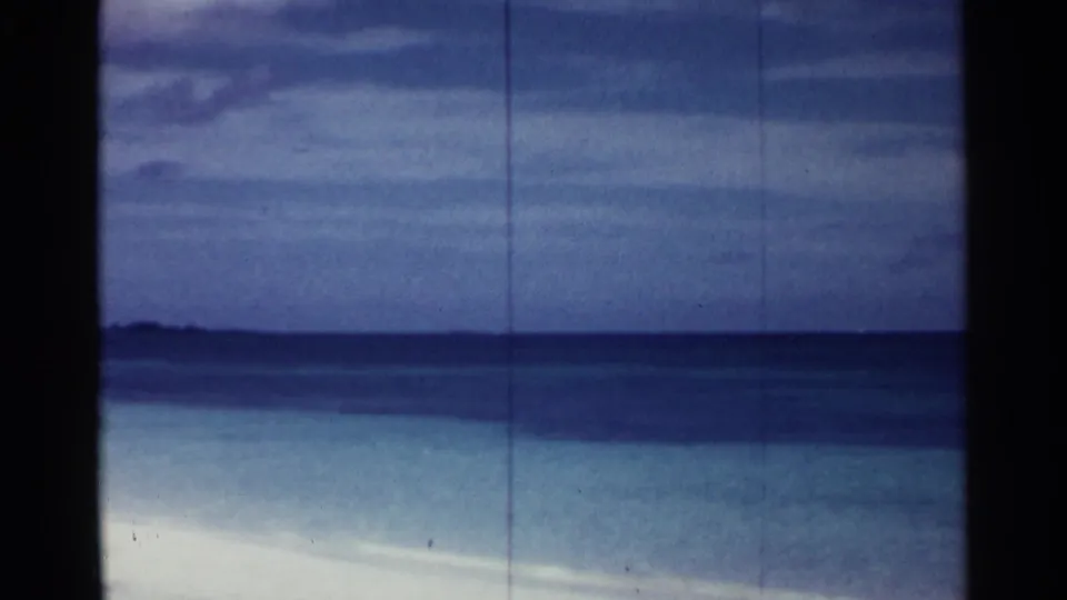 1963 Nassau shoreline view with calm blue water, cloudy sky, and no clearly visible people in this frame.