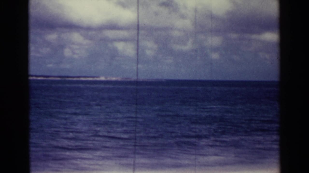 Open ocean under cloudy sky with dark film borders and no people visible.
