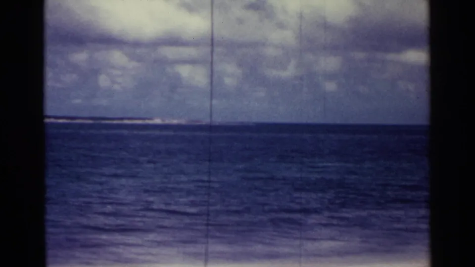1963 Nassau home-movie frame showing open blue water and cloudy sky, with heavy 8mm border shadows and no visible people.