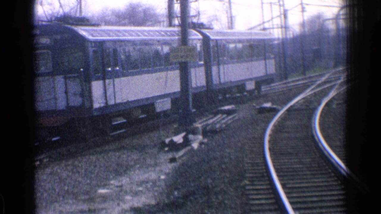 Passenger train cars moving along curved tracks with overhead wires.