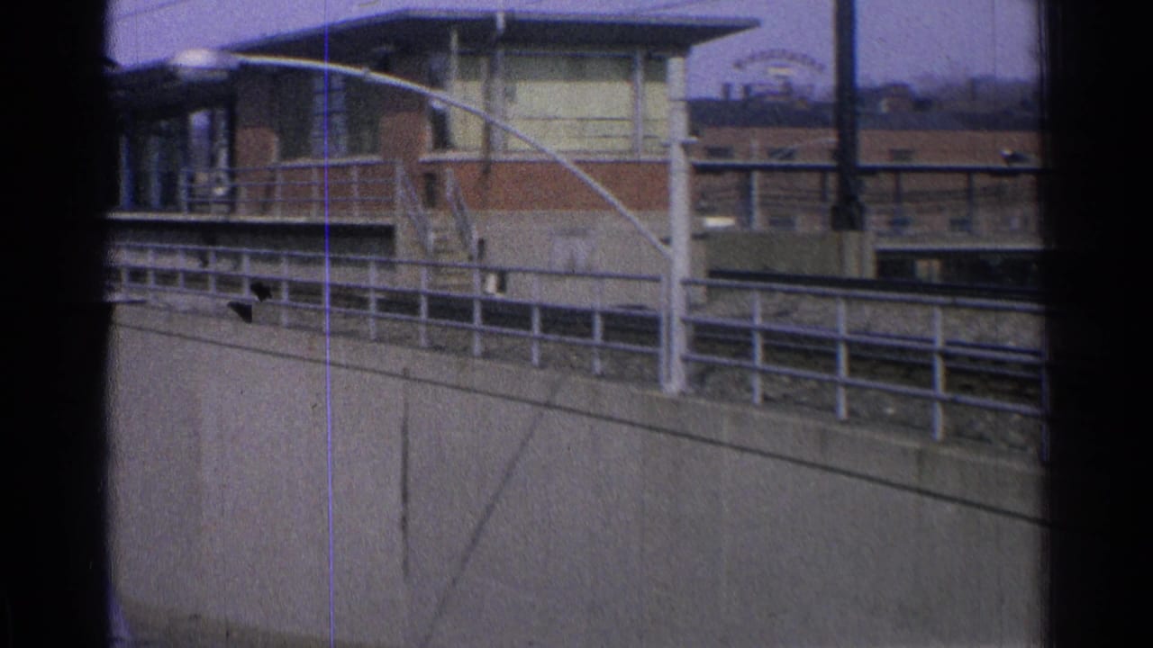 Elevated rail structure with brick building and urban background before the train enters.