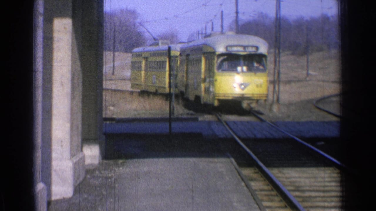 The yellow electric train moves closer to the Ohio station platform, with rails and power lines visible.