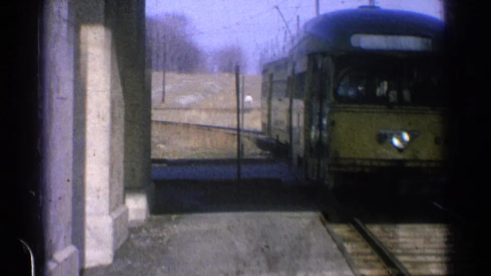 The electric train passes close by the platform, partially leaving the frame in this 1965 Ohio home-movie shot.