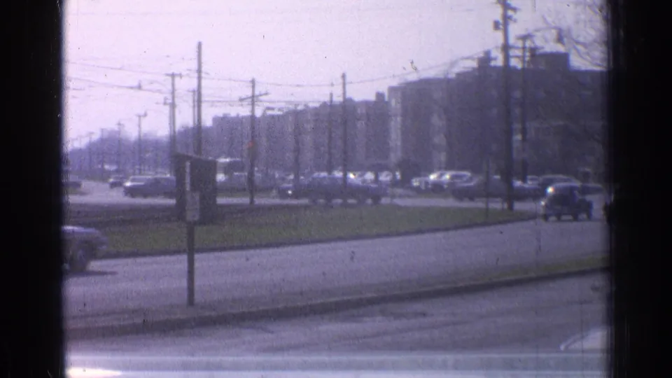 1965 Ohio roadway view showing light downtown traffic, utility poles, trolley or power wires, and a broad grassy median.