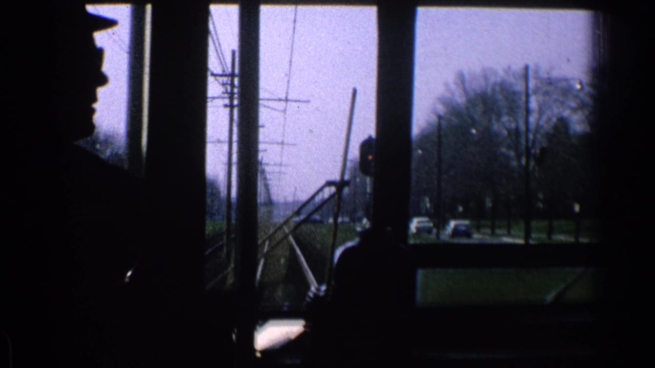 Interior 8mm view from a moving trolley or streetcar in Ohio, with a silhouetted figure and street infrastructure outside.