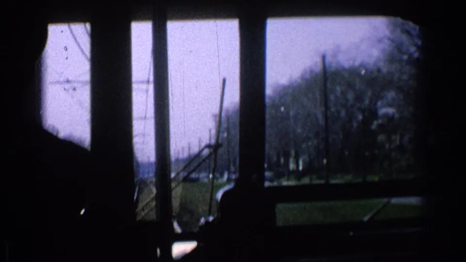 1965 Ohio 8mm train-cab view with silhouetted foreground, window frames, tracks, utility poles, bare trees, and open land ahead.