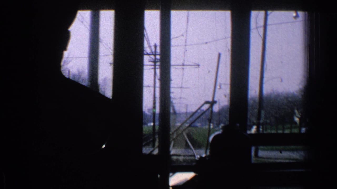 Dark interior silhouette against windows with tracks and overhead wires outside.