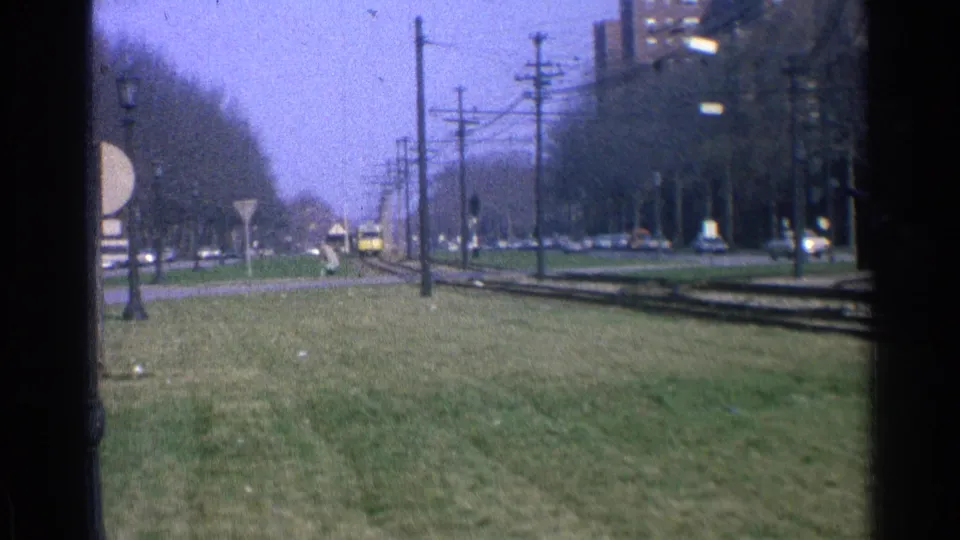 A wide 1965 Ohio view shows a grassy suburban rail corridor with tracks, utility poles, overhead wires, street signs, and a distant yellow rail car.