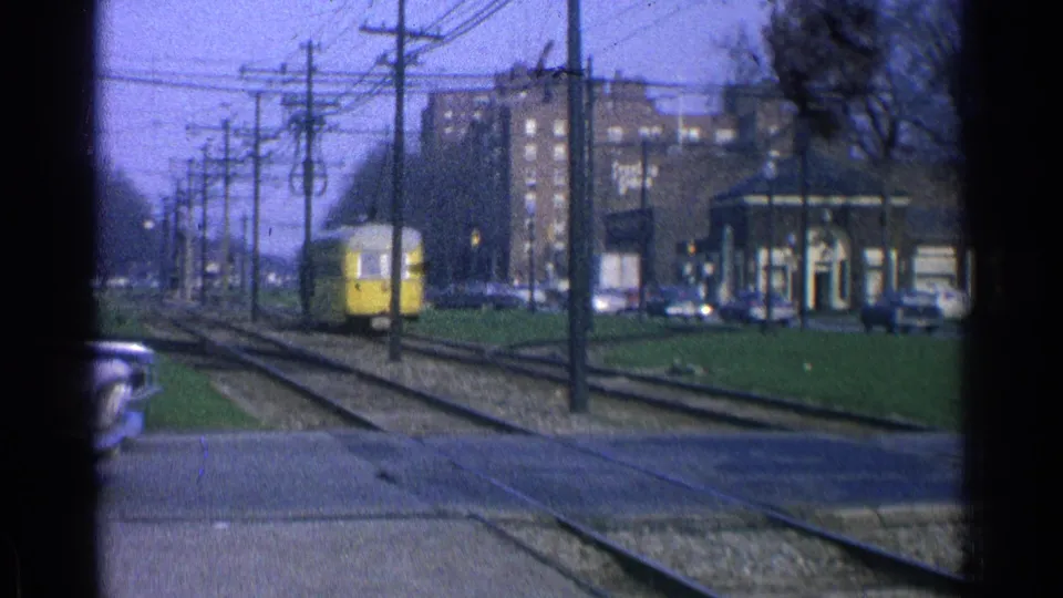 A yellow trolley appears farther down the Ohio street track corridor, with cars, poles, wires, and a low transit structure nearby.
